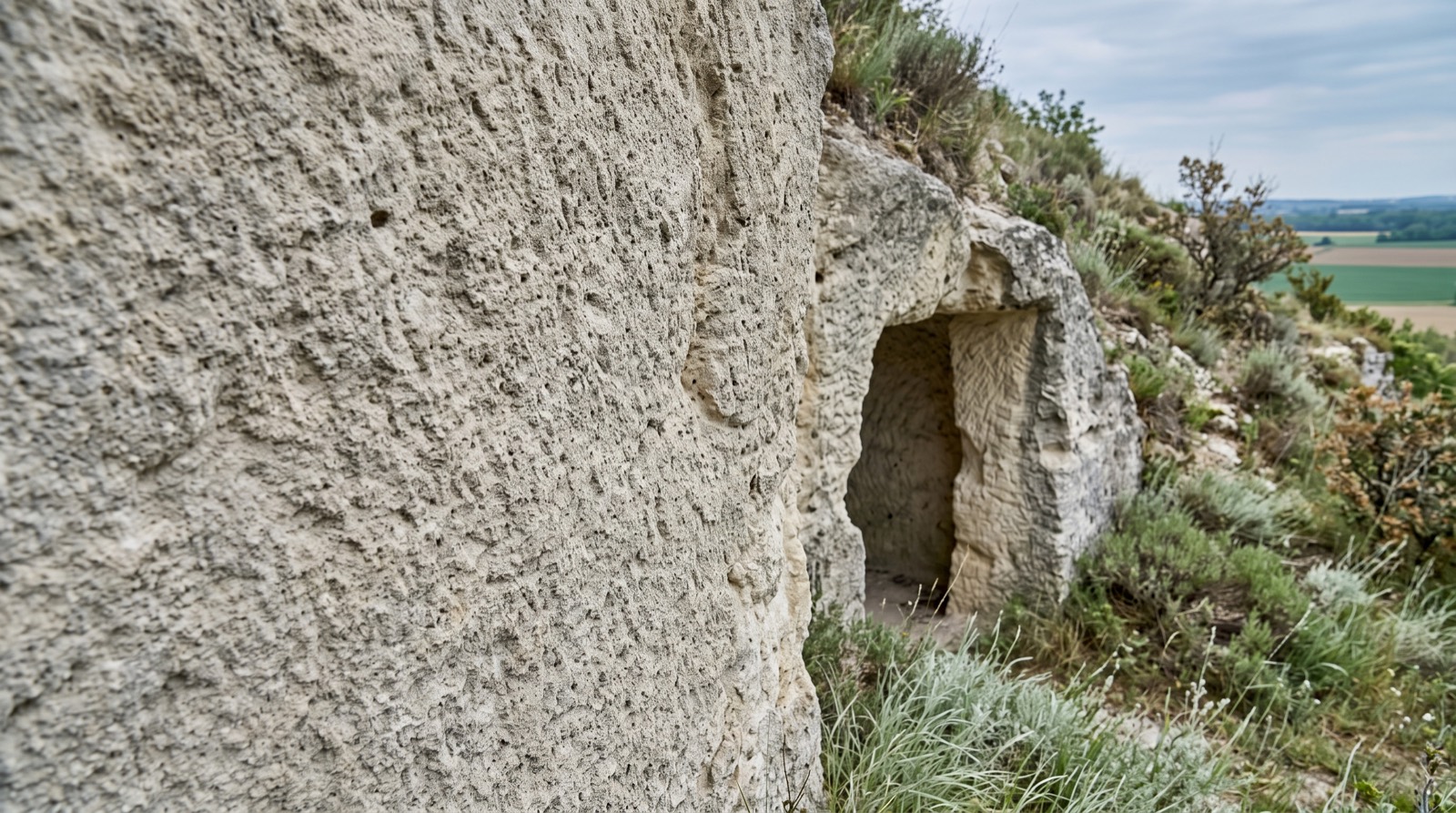 Paroi de tuffeau calcaire du Val de Loire avec l'ouverture d'une cavité troglodytique dans le coteau